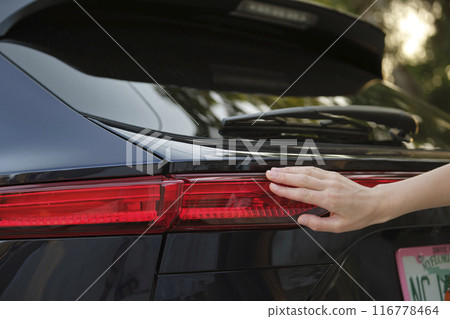 Close-up of human hand on rear car stoplight, checkout before driving. Safety travel concept 116778464