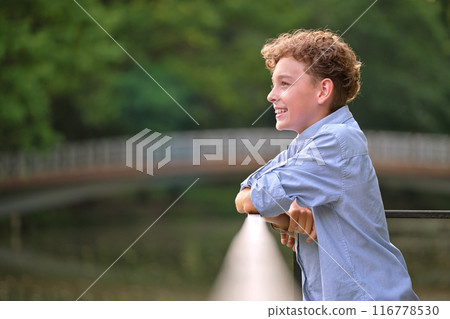 Young happy child boy relaxing in summer park. Positive kid enjoying summertime outdoors. Child wellbeing concept Young happy child boy relaxing in summer park. Positive kid enjoying summertime outdoors. Child wellbeing concept 116778530