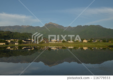 Rice fields before rice planting, reflecting the townscape of Hakushu Town in Hokuto City and the mountain range of the Southern Alps 116779553