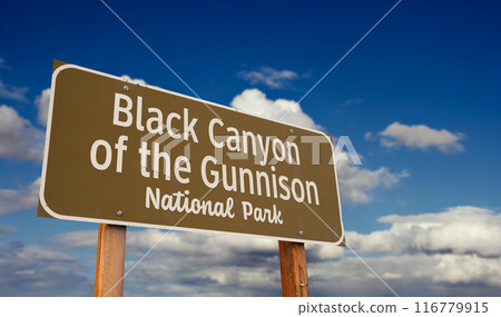 Black Canyon of the Gunnison (Colorado) National Park Road Sign Against Blue Sky and Clouds. Black Canyon of the Gunnison (Colorado) National Park Road Sign Against Blue Sky and Clouds. 116779915