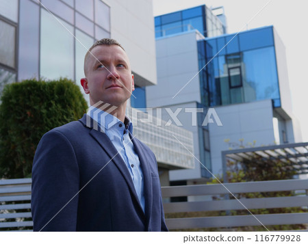 Silhouetted against an office building, Businessman in business attire ponders his next move. The Businessman exudes authority and contemplation. Each glance of the Businessman shows focus Silhouetted against an office building, Businessman in business attire ponders his next move. The Businessman exudes authority and contemplation. Each glance of the Businessman shows focus 116779928