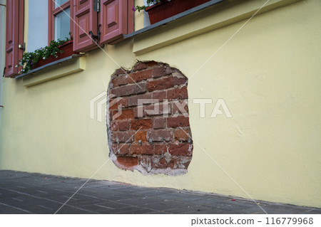 The fallen plaster from the wall of the building from under which the brickwork is visible The fallen plaster from the wall of the building from under which the brickwork is visible 116779968