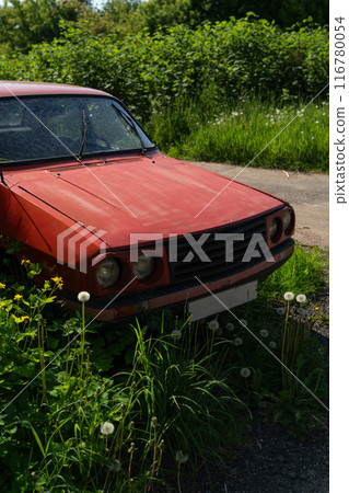 The front of the old Lancia car. Old, forgotten, vintage. A red Lancia car in the village 116780054