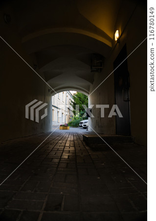 A dark arched passage with a light at the end A dark arched passage with a light at the end 116780149