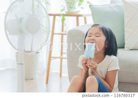 A child eating ice cream in front of a fan during summer vacation 116780317