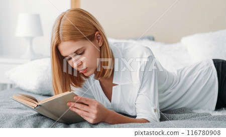 Literature break. Homework study. Young serious focused confident female student reading book learning analyzing researching in bed. Literature break. Homework study. Young serious focused confident female student reading book learning analyzing researching in bed. 116780908