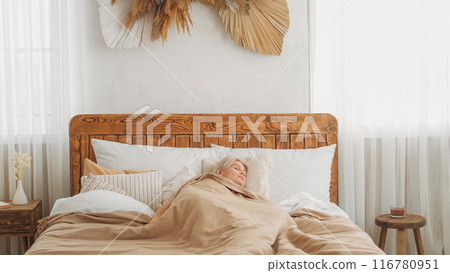 Peaceful sleeping. Weekend rest. Bedroom morning. Calm napping woman enjoying dream laying on comfortable bed in light home interior copy space. 116780951