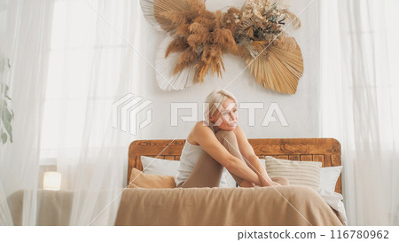 Depression suffer. Lonely sadness. Upset frustrated woman with negative thoughts sitting on bed in light interior bedroom at home copy space. Depression suffer. Lonely sadness. Upset frustrated woman with negative thoughts sitting on bed in light interior bedroom at home copy space. 116780962