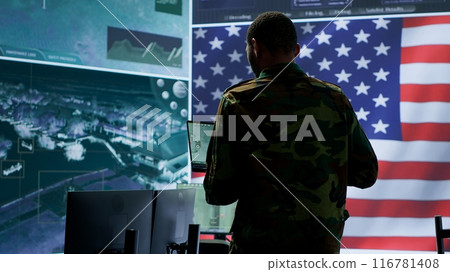 Professionals in US military uniforms operate computers and big screen, working on surveillance and intelligence to ensure national security from a high tech control center. Camera A. Professionals in US military uniforms operate computers and big screen, working on surveillance and intelligence to ensure national security from a high tech control center. Camera A. 116781408