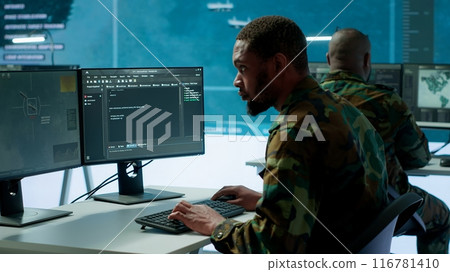 IT expert monitors AI brain intelligence system to collect crucial real time data for a new defense military operation on pc in command post. Security protocols for an intense mission. Camera A. 116781410