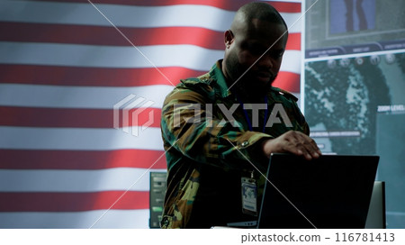 US military personnel work in a modern army command post, safeguarding classified information and state secrets against cyber attacks. Digital warfare and cybersecurity operations. Camera A. US military personnel work in a modern army command post, safeguarding classified information and state secrets against cyber attacks. Digital warfare and cybersecurity operations. Camera A. 116781413