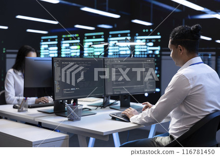Technicians in data center workspace running system diagnostic tests and error checking utilities to fix problems. Employees looking for network issues affecting rigs performance and connectivity 116781450