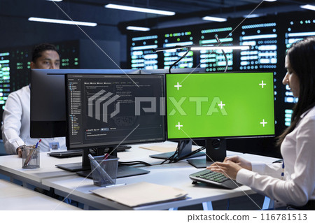 Colleagues working on green screen desktop PC in data center housing storage infrastructure. Coworkers using mockup computer display in server hub workspace filled with networking tech Colleagues working on green screen desktop PC in data center housing storage infrastructure. Coworkers using mockup computer display in server hub workspace filled with networking tech 116781513