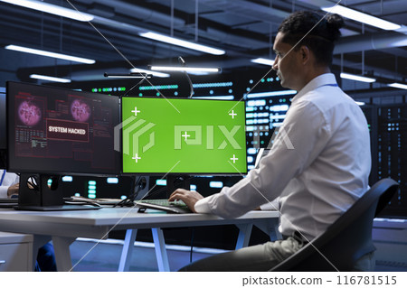Engineer in server hub using green screen PC to stop hacker passing company firewall and stealing sensitive user data. Worker looking at mockup computer display, seeing security breach notification Engineer in server hub using green screen PC to stop hacker passing company firewall and stealing sensitive user data. Worker looking at mockup computer display, seeing security breach notification 116781515