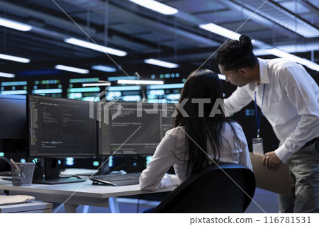 Teamworking technicians in server room looking to find network issues affecting supercomputer performance. IT experts fixing slow data transfer rates in data center equipment 116781531
