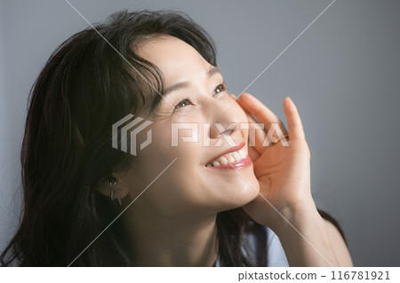 Close-up of a beautiful middle-aged woman in her 50s smiling, touching her cheek, beauty image Close-up of a beautiful middle-aged woman in her 50s smiling, touching her cheek, beauty image 116781921
