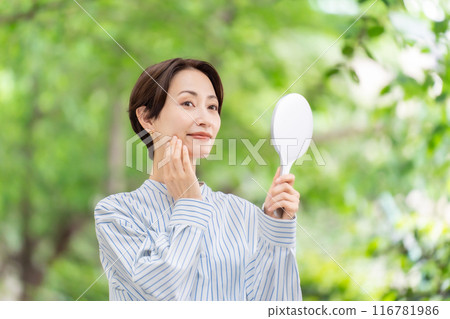 Woman looking in the mirror, fresh greenery Woman looking in the mirror, fresh greenery 116781986