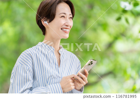 Woman listening to music with earphones, fresh greenery 116781995