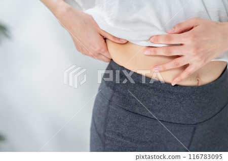 Middle-aged woman touching her stomach, diet Middle-aged woman touching her stomach, diet 116783095
