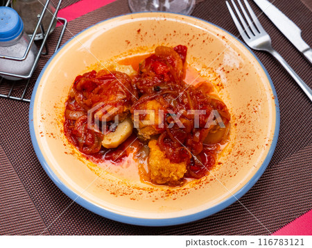 On plate, baked juicy vegetables, complemented by tender cod fillet with xanfaina sauce 116783121