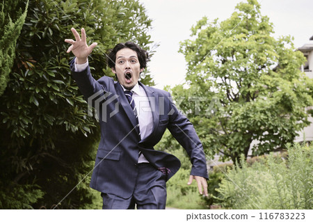 Man in a suit running outdoors 116783223