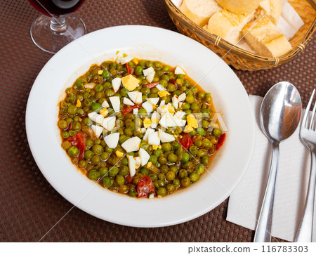 Popular Spanish dish - Peas Murcia Style. Appetizing stewed green peas with ham served with boiled egg 116783303