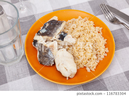 Tender meat of baked cod fillet is garnished with boiled basmati rice. 116783304