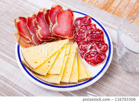Circles of sausage butifarra, slices of prosciutto ham are complemented by triangular sliced cheese 116783306