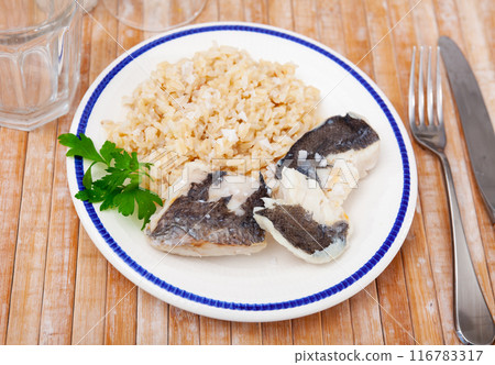 Tender meat of baked cod fillet is garnished with boiled basmati rice. Tender meat of baked cod fillet is garnished with boiled basmati rice. 116783317