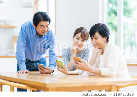Family looking at smartphone in dining room Family looking at smartphone in dining room 116783330