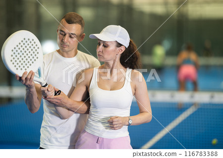 Man teaches adult woman to hold racket 116783388
