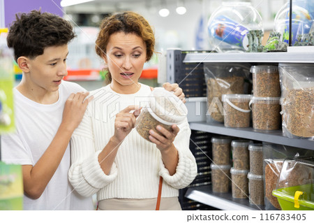 Family mom and son in animal goods store examines packaging of dry food for turtles 116783405