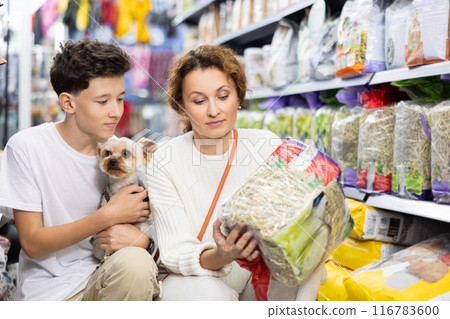 Mom and boy with dog Yorkshire Terrier, take hay from shelf, in pet store. 116783600