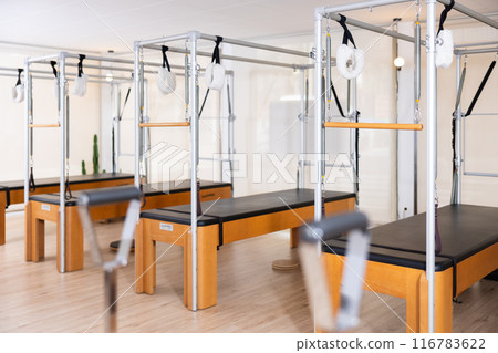 Interior of modern Pilates studio with trapeze tables for exercises Interior of modern Pilates studio with trapeze tables for exercises 116783622