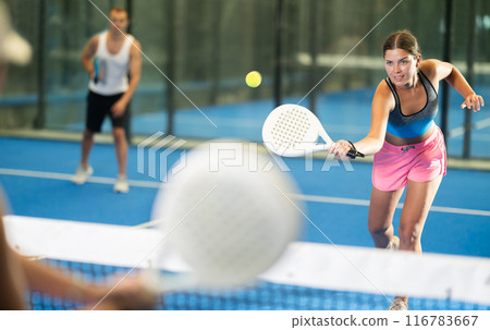 Young woman and man playing tennis against woman 116783667