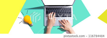 Person using a laptop computer and a light bulb 116784484