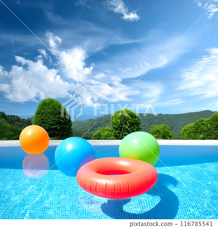 Colorful swim rings and beach balls floating in a blue pool 116785541
