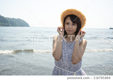 戴著草帽站在海灘上的年輕女子 116785869