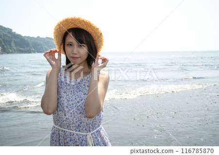 戴著草帽站在海灘上的年輕女子 戴著草帽站在海灘上的年輕女子 116785870