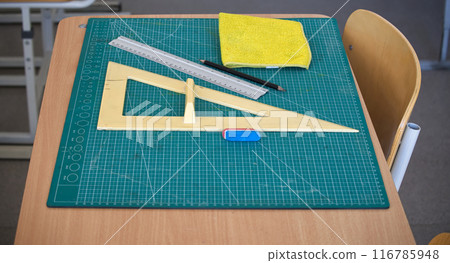 Classroom desk with math tools, ruler, and eraser on a cutting mat 116785948