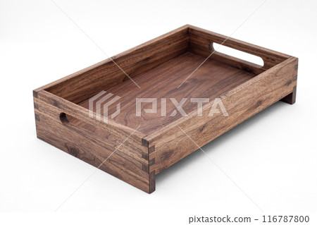 Solid walnut wood tray with dovetail joints and cutout handles on the sides for easy carrying closeup view on white background Solid walnut wood tray with dovetail joints and cutout handles on the sides for easy carrying closeup view on white background 116787800
