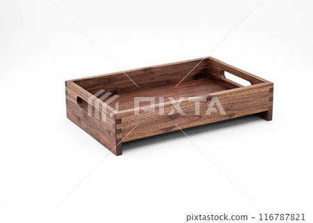 Solid walnut wood tray with dovetail joints and cutout handles on the sides for easy carrying on white background 116787821