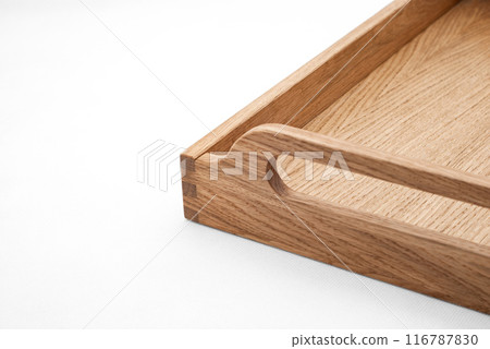Elegant solid oak wood tray with dovetail joints and carved handles on the sides for easy carrying closeup view on white background 116787830