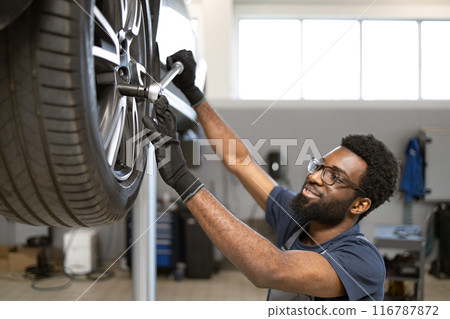 Mechanic working on car wheel in auto repair shop 116787872