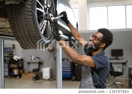 Mechanic working on car wheel in auto repair shop Mechanic working on car wheel in auto repair shop 116787883