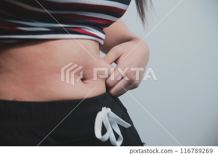Women body fat belly. Obese woman hand holding excessive belly fat. diet lifestyle concept to reduce belly and shape up healthy stomach muscle. Women body fat belly. Obese woman hand holding excessive belly fat. diet lifestyle concept to reduce belly and shape up healthy stomach muscle. 116789269