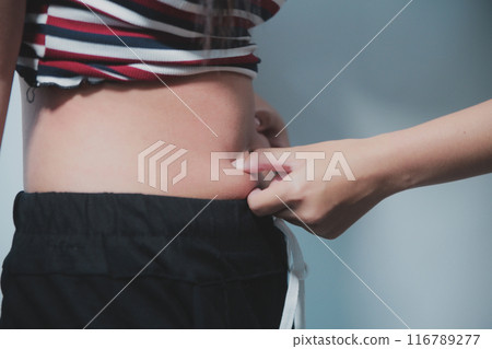 Women body fat belly. Obese woman hand holding excessive belly fat. diet lifestyle concept to reduce belly and shape up healthy stomach muscle. Women body fat belly. Obese woman hand holding excessive belly fat. diet lifestyle concept to reduce belly and shape up healthy stomach muscle. 116789277