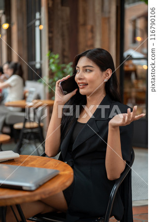 A confident Asian businesswoman is talking on the phone while working remotely from a cafe. 116790106