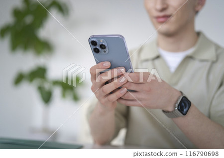 一個修指甲的年輕人的手操作智慧型手機 116790698