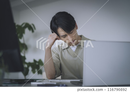 A young man thinking in front of a computer 116790892